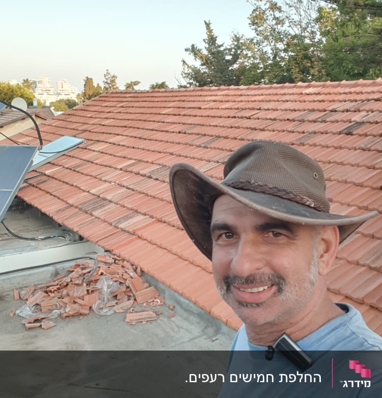 רעפים כתומים על גג עם ערימת שברים בצד